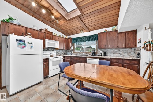 Kitchen with wood-finish cabinetry, white appliances, and a skylight for natural illumination - 13804 87 Street, Edmonton, AB 