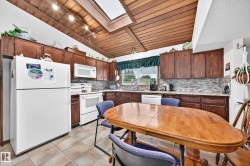 Kitchen with wood-finish cabinetry, white appliances, and a skylight for natural illumination - 