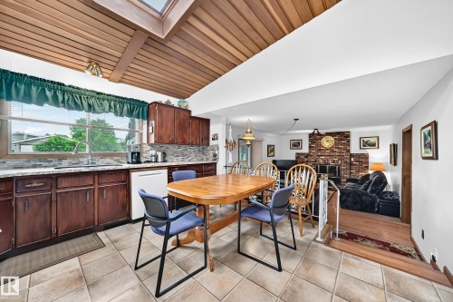 Kitchen and dining area featuring a wood-finish vaulted ceiling with skylight, tile flooring, and dark wood-finish cabinetry - 13804 87 Street, Edmonton, AB 