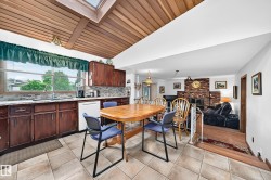 Kitchen and dining area featuring a wood-finish vaulted ceiling with skylight, tile flooring, and dark wood-finish cabinetry - 