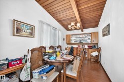 Dining area featuring a vaulted wood-paneled ceiling with exposed beams, wood-finish flooring, and built-in cabinetry with glass-front display storage - 