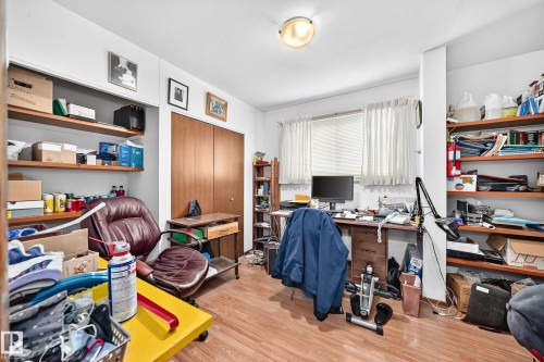 Room featuring wood-finish flooring, two sets of built-in shelving, a window with blinds, and a closet with bi-fold doors - 13804 87 Street, Edmonton, AB 