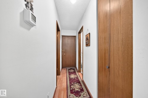 Hallway featuring wood-finish flooring, white walls, and wood-paneled doors - 13804 87 Street, Edmonton, AB 
