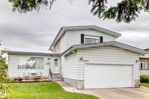 Two-story residence featuring light-colored siding, an attached garage, and a large front picture window - 13804 87 Street, Edmonton, AB 
