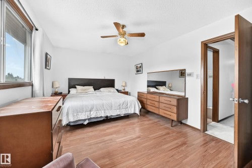 Bright room featuring wood-finish flooring, a ceiling fan with integrated lighting, and a window with a roller shade - 13804 87 Street, Edmonton, AB 