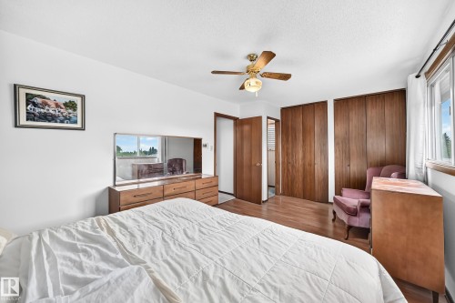 Bright interior featuring wood-finish flooring, a ceiling fan with integrated lighting, and multiple wood-panel closet doors - 13804 87 Street, Edmonton, AB 