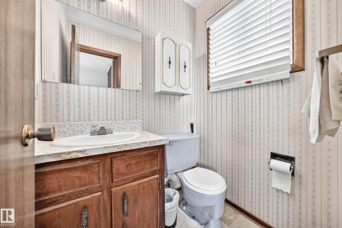Bathroom with a wood-finish vanity, a white countertop, and an integrated sink - 13804 87 Street, Edmonton, AB 