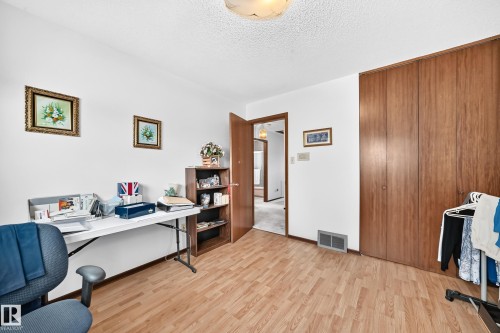 Versatile room featuring wood-finish flooring, white walls, and a textured ceiling - 13804 87 Street, Edmonton, AB 