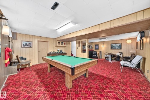 Spacious lower-level room featuring wood-paneled walls and a drop ceiling with integrated lighting - 13804 87 Street, Edmonton, AB 