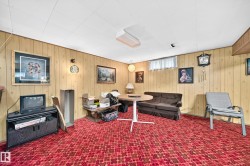 Recreation room featuring wood-panel walls, patterned red carpeting, a drop ceiling, and a high-set window - 