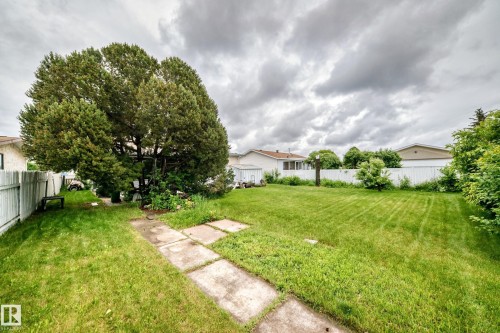Expansive backyard featuring a mature tree, manicured lawn, and white picket fencing - 13804 87 Street, Edmonton, AB 