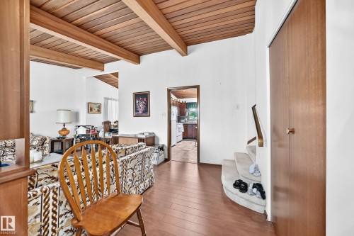 Living area featuring a wood-panel accent ceiling, exposed beams, and wood-finish flooring - 13804 87 Street, Edmonton, AB 