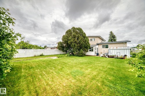 Expansive backyard featuring a manicured lawn, established perimeter foliage, and a white picket fence - 13804 87 Street, Edmonton, AB 