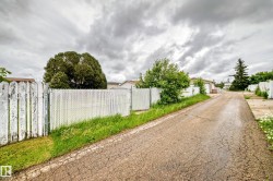 Gated access with a combination of wood fencing and chain-link fencing, bordering a paved driveway - 