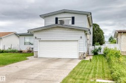 Two-story residence featuring light-colored siding, a prominent attached garage with a white door, and a concrete driveway - 
