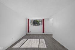 Bright interior featuring wood-finish flooring, white walls, and a large window - 