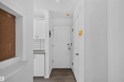 Entryway featuring wood-finish flooring, white walls, and a solid white door - 
