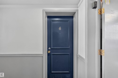 Navy blue paneled entry door with brass hardware and numbered plaque - 6 10230 122 Street Nw, Edmonton, AB 