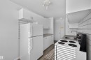 Compact kitchen featuring white cabinetry, a stainless steel sink, a full-size refrigerator, an electric range, and wood-finish flooring - 6 10230 122 Street Nw, Edmonton, AB 