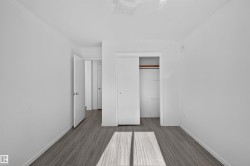 Neutral white walls, wood-finish flooring, and a built-in closet with sliding doors - 