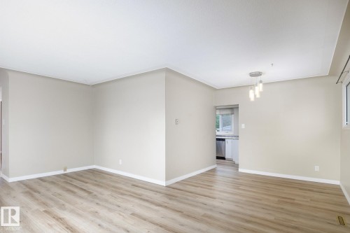 Expansive interior featuring light wood-finish flooring, neutral wall paint, and white baseboards - 9607 75 Street, Edmonton, AB 