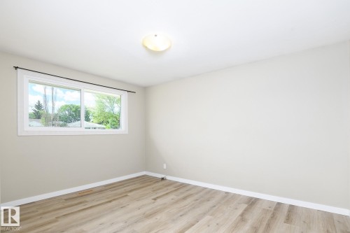 Bright room with wood-finish flooring and a white trim baseboard - 9607 75 Street, Edmonton, AB 