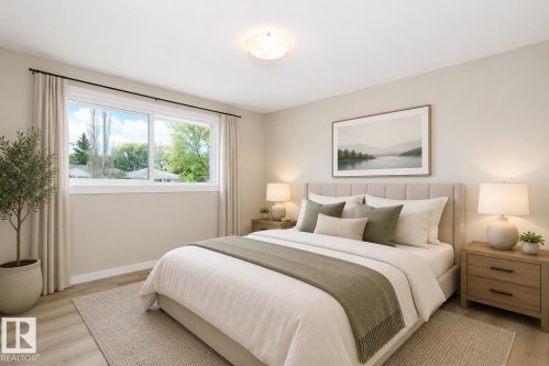 Spacious bedroom featuring light-toned walls, wood-finish flooring, and a large window - 9607 75 Street, Edmonton, AB 