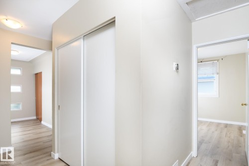 Hallway featuring wood-finish flooring, white sliding closet doors, and recessed lighting - 9607 75 Street, Edmonton, AB 
