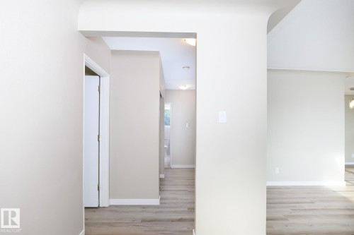 Expansive interior hallway featuring light-colored walls, wood-finish flooring, white baseboards, and recessed lighting - 9607 75 Street, Edmonton, AB 