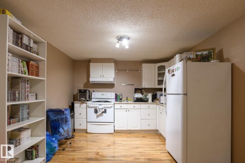 Kitchen featuring white cabinetry, white appliances, and wood-finish flooring - 9607 75 Street, Edmonton, AB 