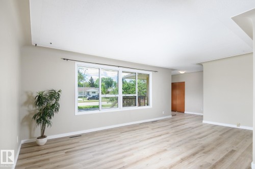 Spacious interior featuring wood-finish flooring, a large multi-pane window, neutral wall tones, and white trim - 9607 75 Street, Edmonton, AB 