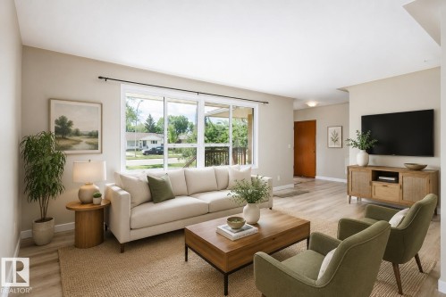 Spacious living area featuring light wood-finish flooring, a large window providing ample natural light, neutral wall colors, recessed ceiling lighting, and a solid wood entry door - 9607 75 Street, Edmonton, AB 