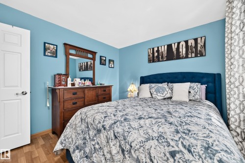 Bedroom featuring wood-finish flooring, a white paneled door, and a light blue wall finish - 11708 138 Avenue Nw, Edmonton, AB 