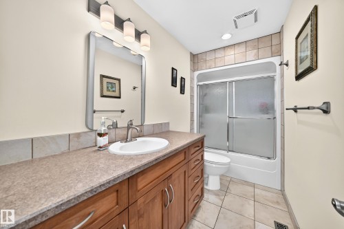 Bathroom featuring a vanity with a light brown countertop, under-mount sink, and wood-finish cabinetry - 11708 138 Avenue Nw, Edmonton, AB 