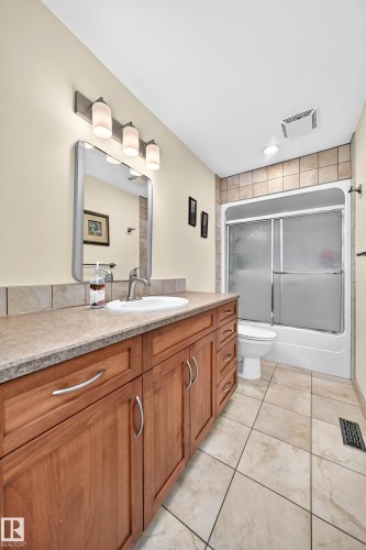 Bathroom featuring a wood-finish vanity with a light-colored countertop and integrated sink - 11708 138 Avenue Nw, Edmonton, AB 