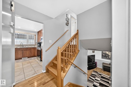 Split-level entrance featuring natural wood flooring and a staircase with a matching wood railing - 11708 138 Avenue Nw, Edmonton, AB 