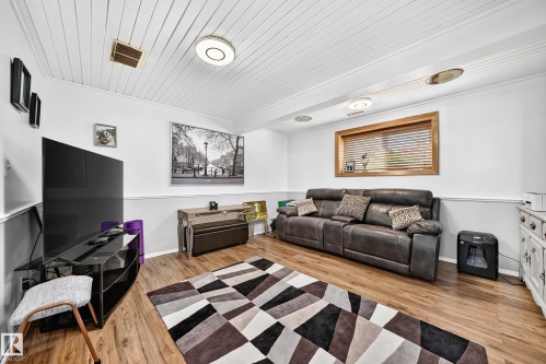 Spacious room featuring wood-finish flooring, white paneled ceilings, and light-toned walls with chair rail molding - 11708 138 Avenue Nw, Edmonton, AB 