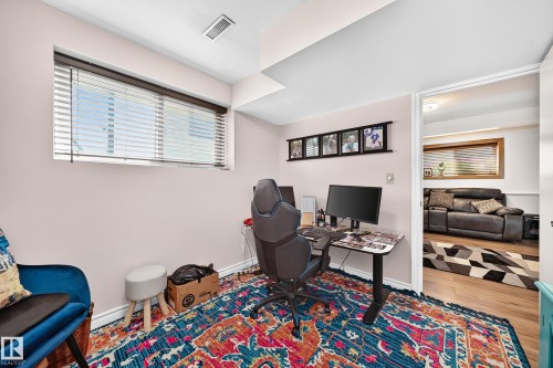 Dedicated room featuring a window with horizontal blinds, light-colored walls, ceiling ventilation, and wood-finish flooring visible through the doorway - 11708 138 Avenue Nw, Edmonton, AB 