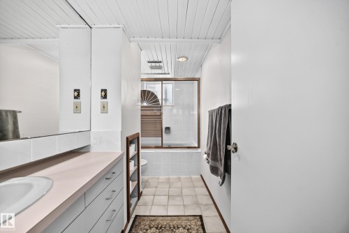 Bathroom featuring a built-in vanity with integrated sink, full-width mirror, and panelled ceiling - 11708 138 Avenue Nw, Edmonton, AB 