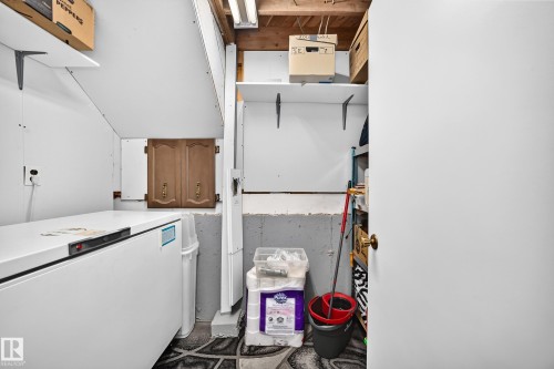 Utility area featuring white paneling, overhead shelving, exposed ceiling joists, and a built-in wood cabinet - 11708 138 Avenue Nw, Edmonton, AB 