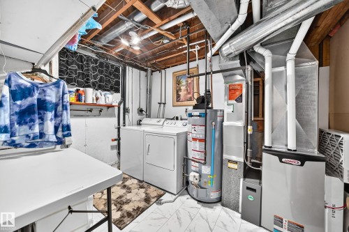 Utility space featuring a washer and dryer, water heater, furnace, and exposed ceiling joists - 11708 138 Avenue Nw, Edmonton, AB 