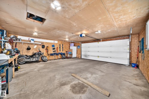 Spacious garage with a concrete floor, plywood walls, and an overhead garage door - 11708 138 Avenue Nw, Edmonton, AB 