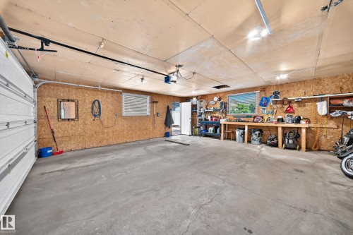 Spacious garage featuring a concrete floor, built-in workbench, and multiple overhead light fixtures - 11708 138 Avenue Nw, Edmonton, AB 