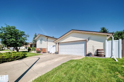 Exterior featuring a two-car garage with a white panel door, light-colored siding, and a concrete driveway - 11708 138 Avenue Nw, Edmonton, AB 