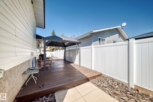 Expansive wood-finish deck with a built-in gazebo, complemented by a white privacy fence and exterior siding - 11708 138 Avenue Nw, Edmonton, AB 