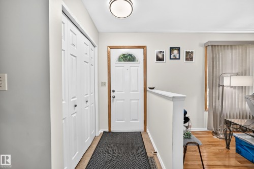 Entryway featuring a white paneled door with an arched window, light wood-finish trim, and a semi-flush mount ceiling light - 11708 138 Avenue Nw, Edmonton, AB 