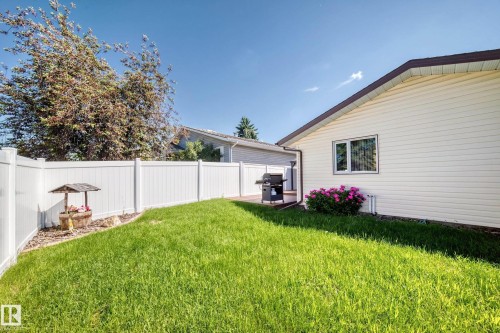 Spacious backyard featuring a manicured lawn, white privacy fencing, and mature trees - 11708 138 Avenue Nw, Edmonton, AB 