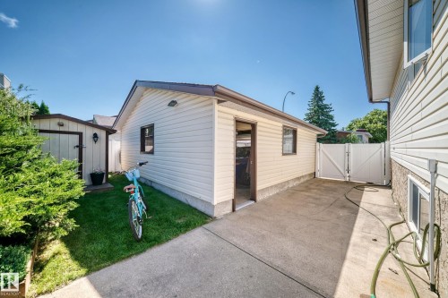 Detached garage with horizontal siding, a side entry door, and a brown trimmed window - 11708 138 Avenue Nw, Edmonton, AB 