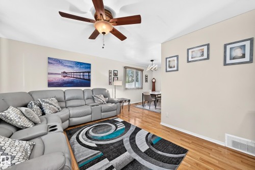 Living area featuring hardwood flooring, a ceiling fan with integrated lighting, and neutral wall tones - 11708 138 Avenue Nw, Edmonton, AB 