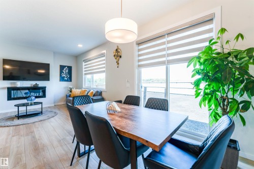 Open-concept living area with wood-finish flooring, a built-in electric fireplace, and recessed lighting - 8426 228A Street Nw, Edmonton, AB - Indoor Photo Showing Dining Room